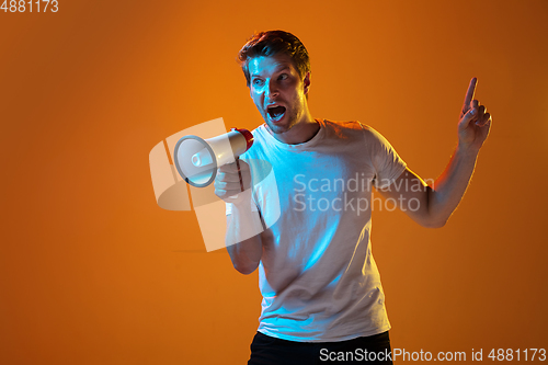 Image of Caucasian beautiful young man\'s portrait on gradient orange studio background, emotional and expressive. Copyspace for ad.