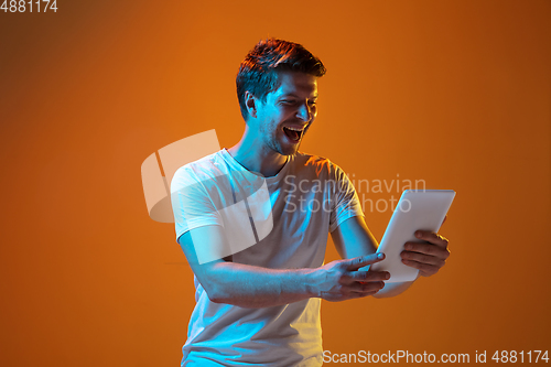 Image of Caucasian beautiful young man\'s portrait on gradient orange studio background, emotional and expressive. Copyspace for ad.