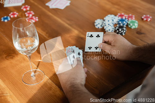 Image of Close up group of happy mature friends playing cards and drinking wine