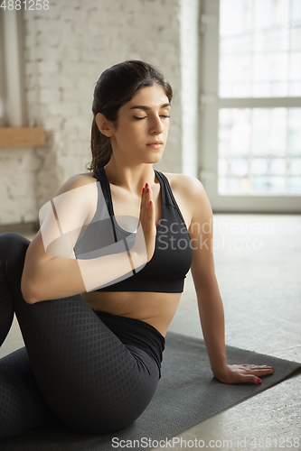 Image of Sporty young muslim woman taking yoga lessons online and practice at home