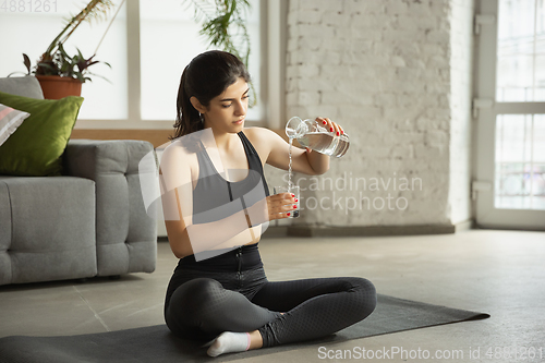 Image of Sporty young muslim woman taking yoga lessons online and practice at home