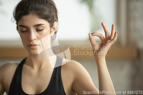 Image of Sporty young muslim woman taking yoga lessons online and practice at home, close up