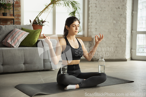 Image of Sporty young muslim woman taking yoga lessons online and practice at home