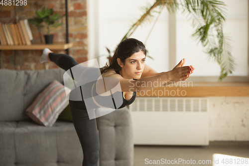 Image of Sporty young muslim woman taking yoga lessons online and practice at home