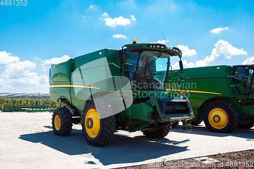 Image of Tractor, combine at a field in sunlight. Confident, bright colors