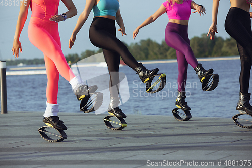Image of Beautiful women in sportswear jumping in a kangoo jumps shoes at the street on summer\'s sunny day