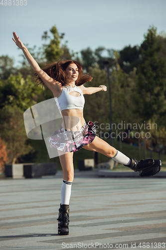 Image of Beautiful woman in sportswear jumping in a kangoo jumps shoes at the street on summer\'s sunny day