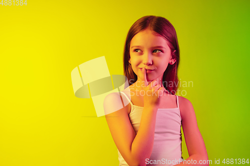 Image of Little caucasian girl\'s portrait isolated on gradient background in neon light. Concept of human emotions, facial expression, modern gadgets and technologies. Copyspace.