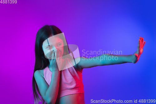 Image of Little caucasian girl\'s portrait isolated on gradient pink-blue background in neon light.