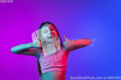 Image of Little caucasian girl\'s portrait isolated on gradient pink-blue background in neon light.