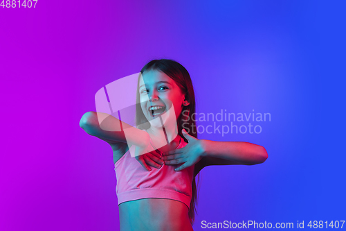 Image of Little caucasian girl\'s portrait isolated on gradient pink-blue background in neon light.