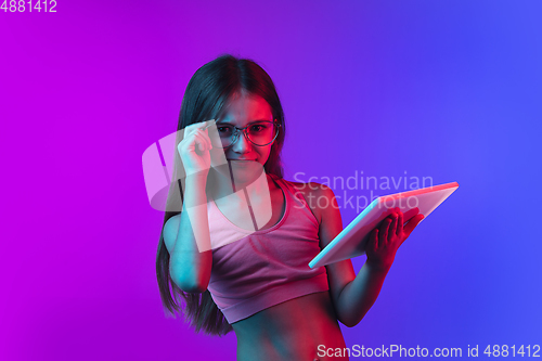 Image of Little caucasian girl\'s portrait isolated on gradient pink-blue background in neon light.