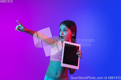 Image of Little caucasian girl\'s portrait isolated on gradient pink-blue background in neon light.