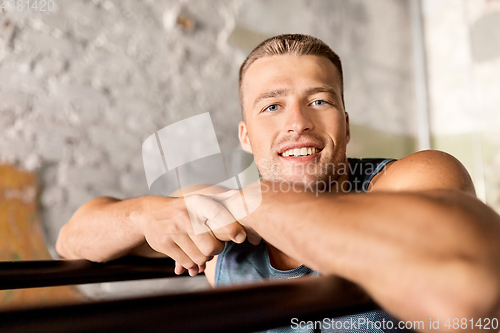 Image of smiling young man at parallel bars in gym