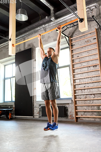 Image of man exercising on bar and doing pull-ups in gym