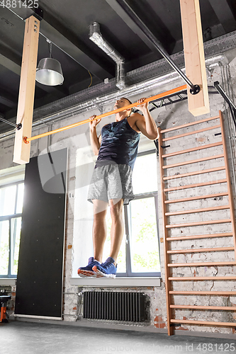 Image of man exercising on bar and doing pull-ups in gym