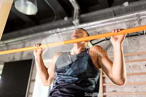 Image of man exercising on bar and doing pull-ups in gym