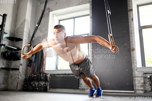 Image of man doing exercising on gymnastic rings in gym