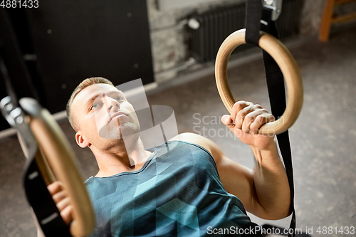 Image of man doing exercising on gymnastic rings in gym