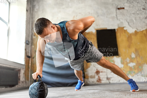 Image of young man doing kettlebell push-ups in gym