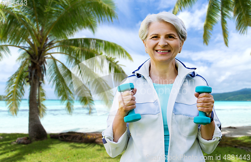 Image of senior woman with dumbbells exercising at park