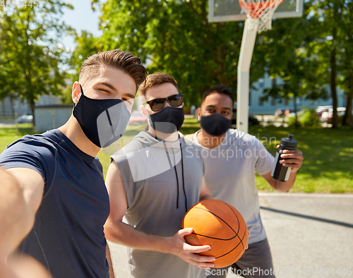 Image of happy men taking selfie on basketball playground