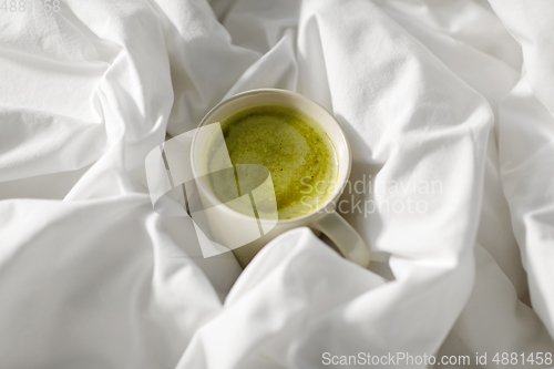 Image of cup of matcha tea in bed at home