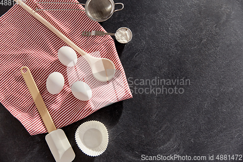 Image of eggs, flour, spoon, spatula, strainer and towel