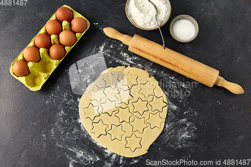 Image of dough, rolling pin, eggs, flour and sugar on table