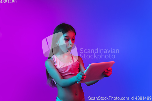 Image of Little caucasian girl\'s portrait isolated on gradient pink-blue background in neon light.