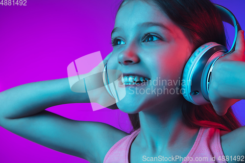 Image of Little caucasian girl\'s portrait isolated on gradient pink-blue background in neon light.