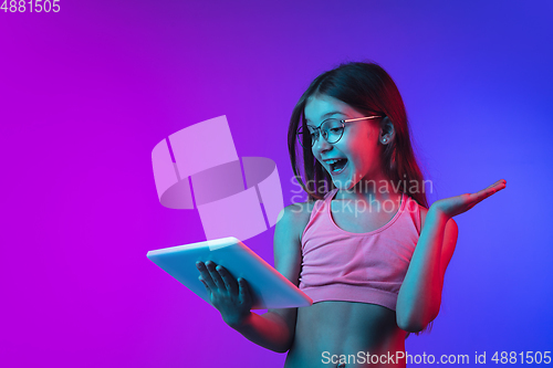 Image of Little caucasian girl\'s portrait isolated on gradient pink-blue background in neon light.