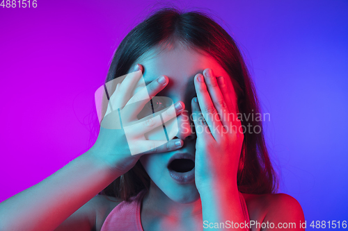 Image of Little caucasian girl\'s portrait isolated on gradient pink-blue background in neon light.