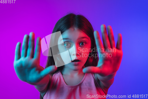 Image of Little caucasian girl\'s portrait isolated on gradient pink-blue background in neon light.