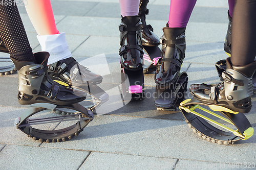 Image of Beautiful women in sportswear jumping in a kangoo jumps shoes at the street on summer\'s sunny day