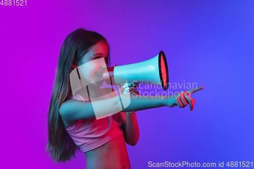 Image of Little caucasian girl\'s portrait isolated on gradient pink-blue background in neon light.