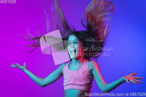 Image of Little caucasian girl\'s portrait isolated on gradient pink-blue background in neon light.