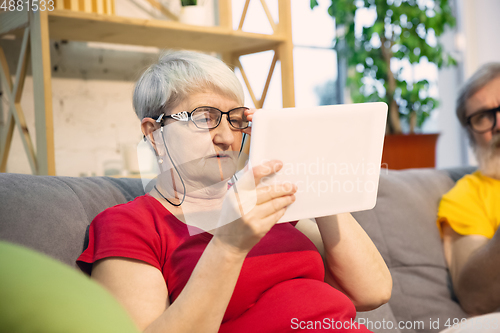 Image of Couple of seniors spending time together being quarantined - caucasians mature and retired man and woman using modern gadgets, talking, drinking tea