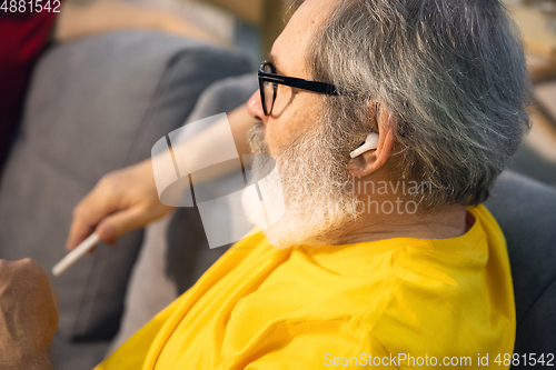 Image of Mature man spending time being quarantined - caucasian man using modern gadgets, drinking tea