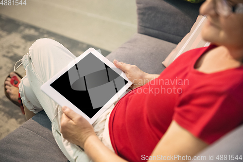 Image of Mature woman spending time being quarantined - caucasian woman using modern gadgets, drinking tea