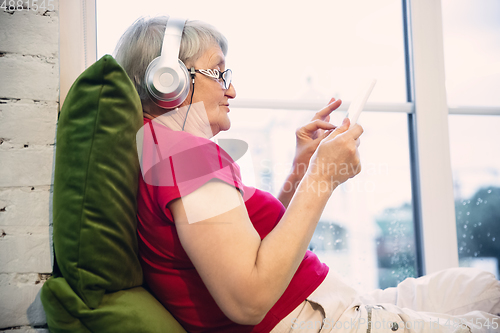 Image of Mature woman spending time being quarantined - caucasian woman using modern gadgets, drinking tea