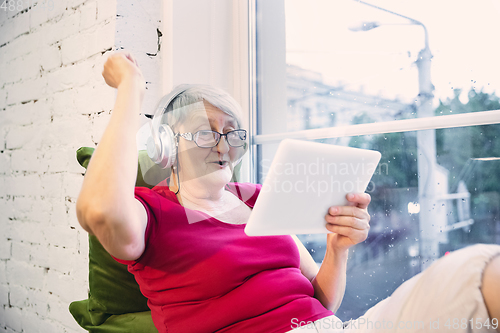 Image of Mature woman spending time being quarantined - caucasian woman using modern gadgets, drinking tea