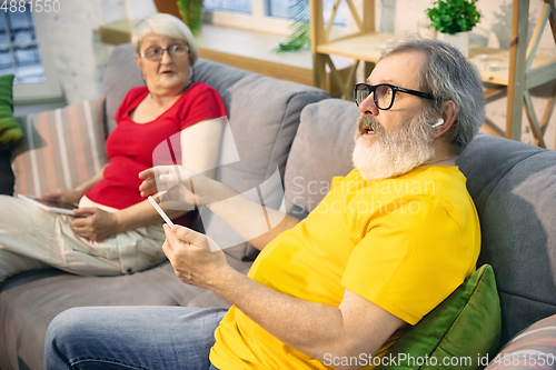 Image of Couple of seniors spending time together being quarantined - caucasians mature and retired man and woman using modern gadgets, talking, drinking tea