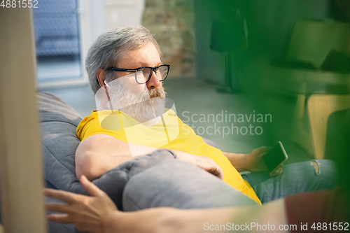 Image of Couple of seniors spending time together being quarantined - caucasians mature and retired man and woman using modern gadgets, talking, drinking tea