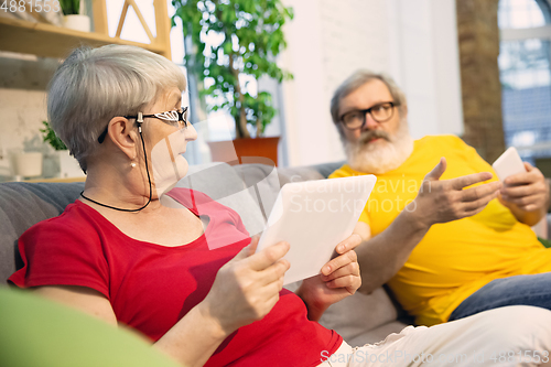 Image of Couple of seniors spending time together being quarantined - caucasians mature and retired man and woman using modern gadgets, talking, drinking tea