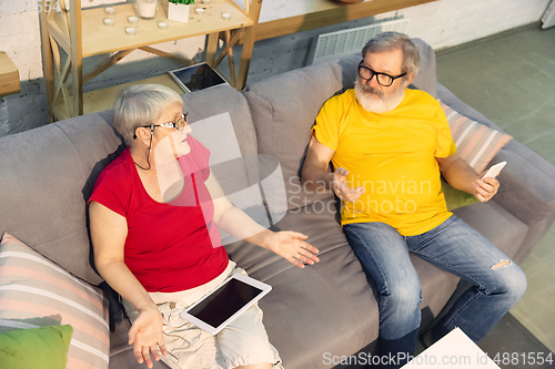 Image of Couple of seniors spending time together being quarantined - caucasians mature and retired man and woman using modern gadgets, talking, drinking tea