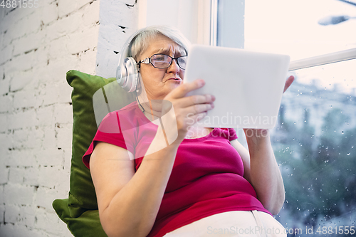 Image of Mature woman spending time being quarantined - caucasian woman using modern gadgets, drinking tea