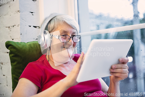 Image of Mature woman spending time being quarantined - caucasian woman using modern gadgets, drinking tea