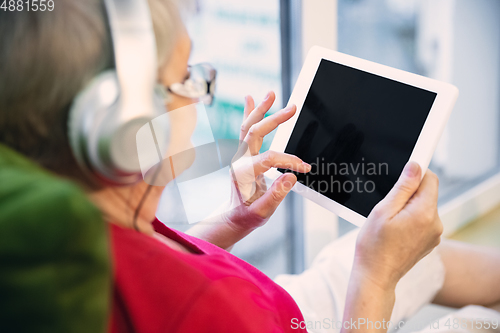 Image of Mature woman spending time being quarantined - caucasian woman using modern gadgets, drinking tea