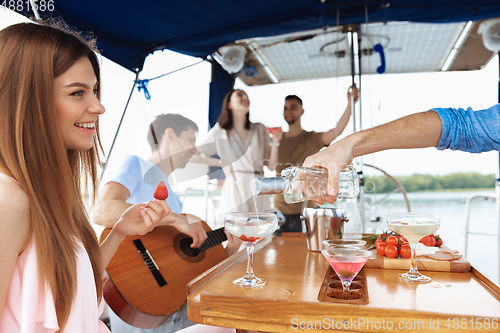 Image of Group of happy friends drinking vodka cocktails at boat party outdoor, cheerful and happy